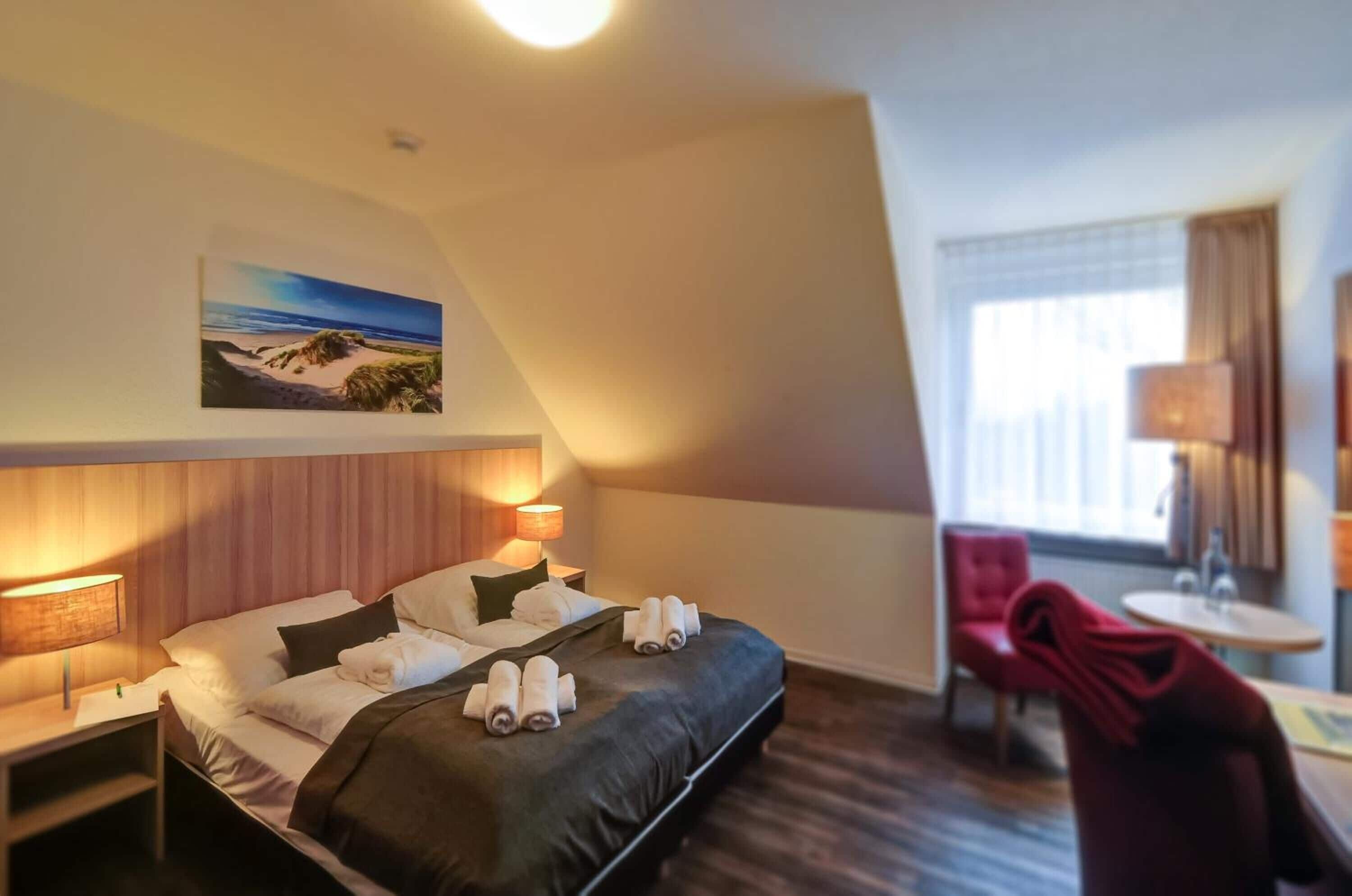 Une chambre d’hôtel avec un lit, un bureau, une chaise, une lampe et un tableau au mur.