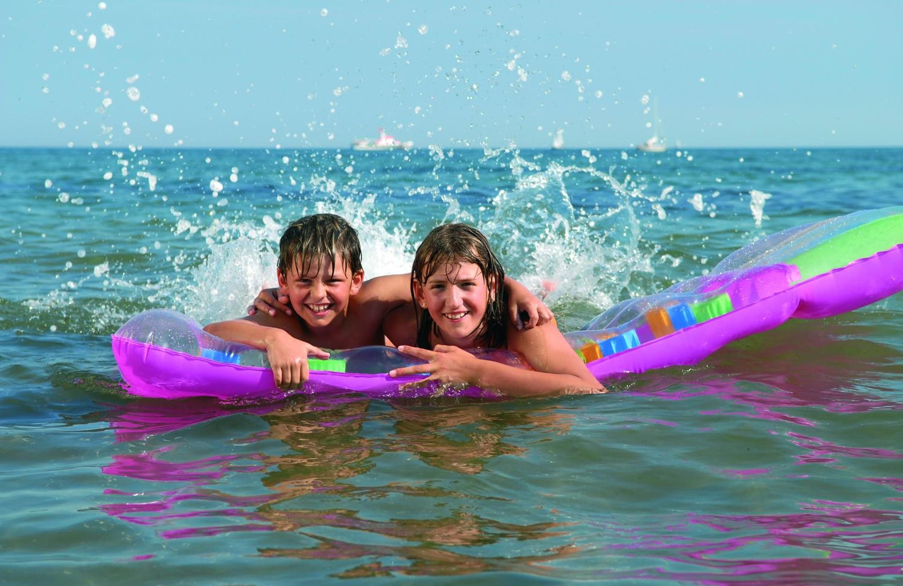 Two people lying on a purple inflatable float in the ocean.