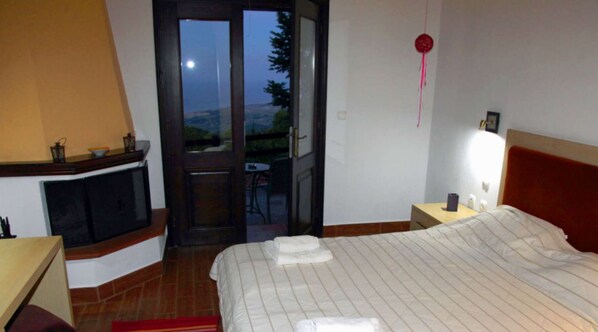 A bedroom with a bed, a nightstand, a dresser, a window, and a door leading to a balcony.