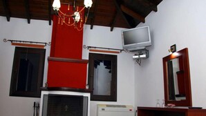 Een hotelkamer met een open haard, een televisie, een spiegel en een bed met handdoeken.