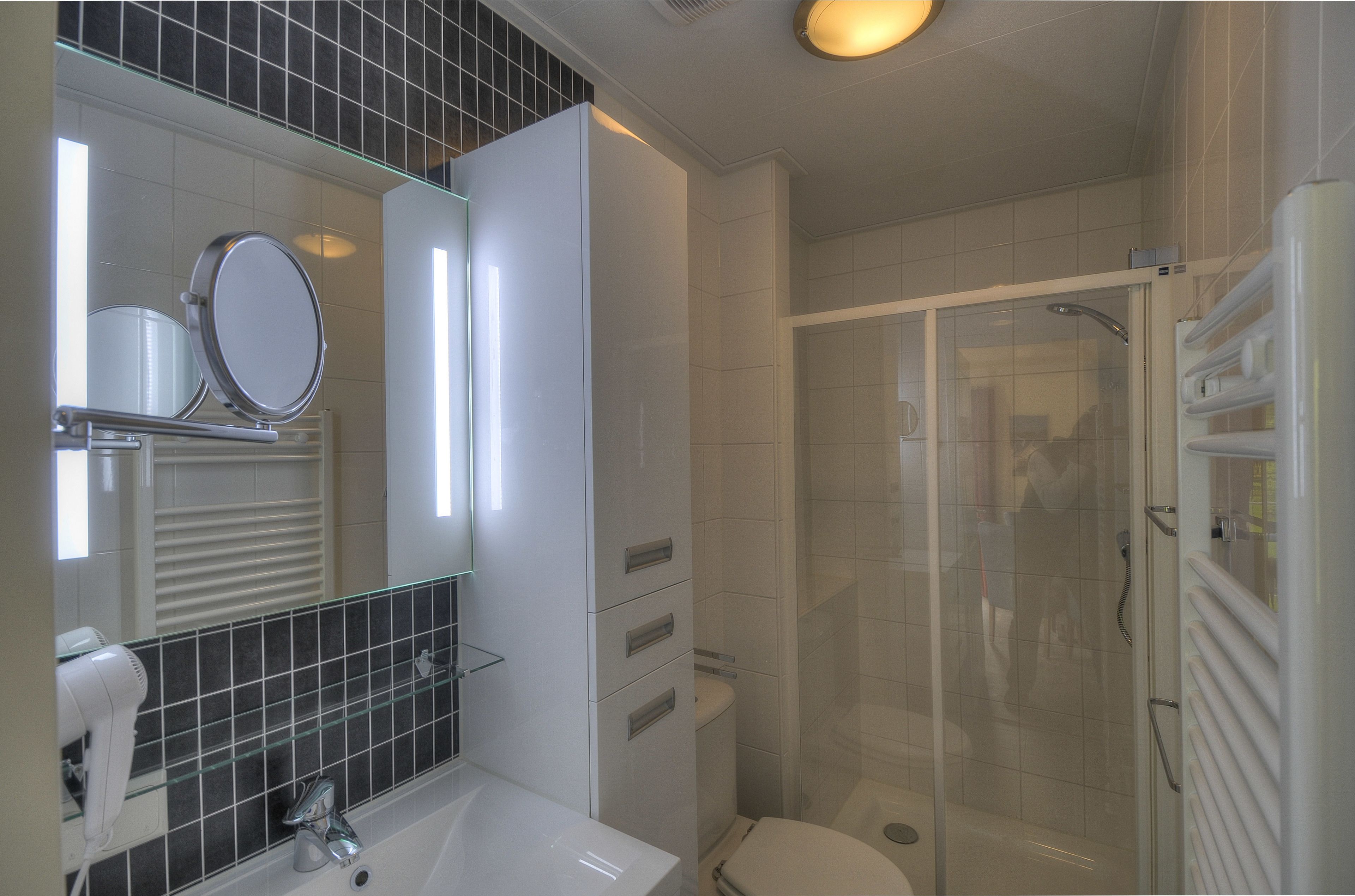 A modern bathroom with a glass shower enclosure, a white sink, and a mirror above the sink.