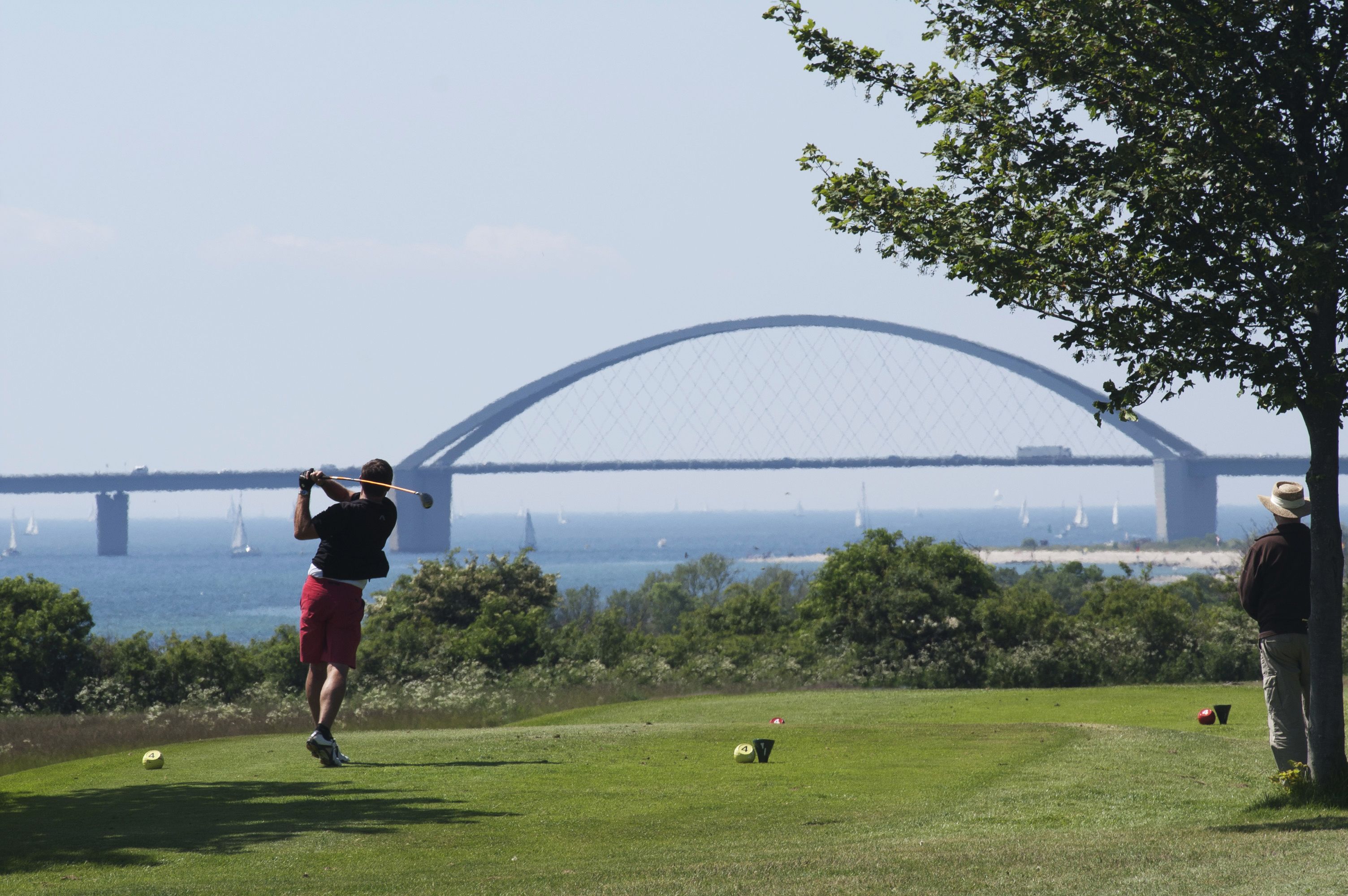 A golf course with a large bridge in the background.