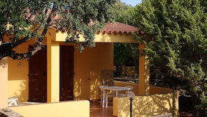 Un edificio amarillo con tejado de tejas, un patio con mesa y sillas, y una valla de madera.