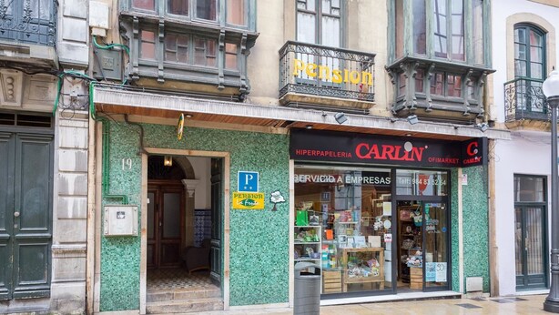 A storefront with a green mosaic exterior, a visible entrance, and a 'Pension' sign above. - Pensión La Fruta (Aviles)