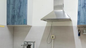 A modern kitchen with a stainless steel sink, wooden cabinets, and a built-in range hood. - Pensión La Fruta (Aviles)