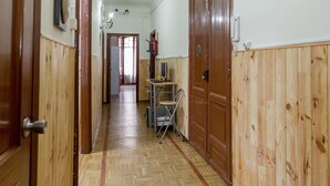 A hallway with wooden paneling, a folding chair, and a small table with a chair. - Pensión La Fruta (Aviles)