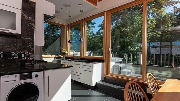 A modern kitchen with a built-in washer, large windows, and a dining area with a view of the outdoors. - Sugarloaf Inn (Kingfield)