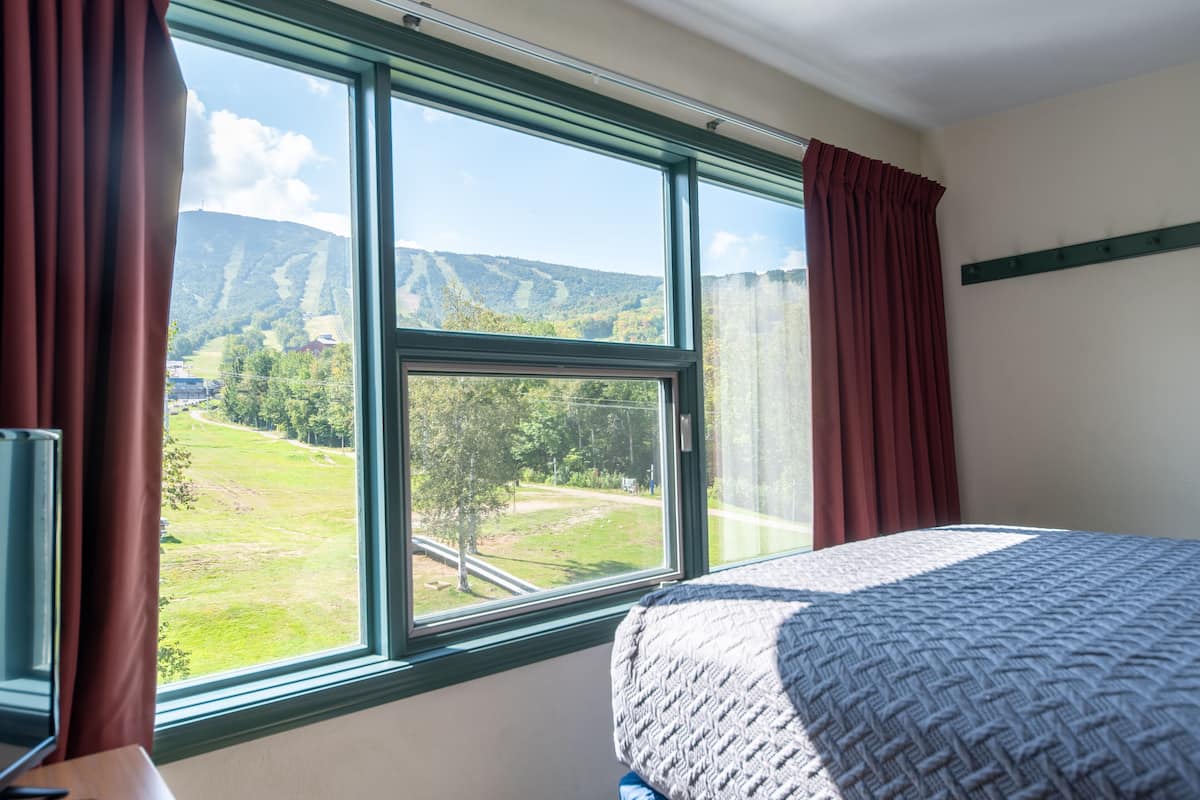 Un dormitorio con un ventanal que ofrece vistas a un paisaje verde y colinas.