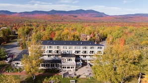 A multi-story hotel with a central courtyard, surrounded by autumn foliage and mountains in the background. - Sugarloaf Inn (Kingfield)