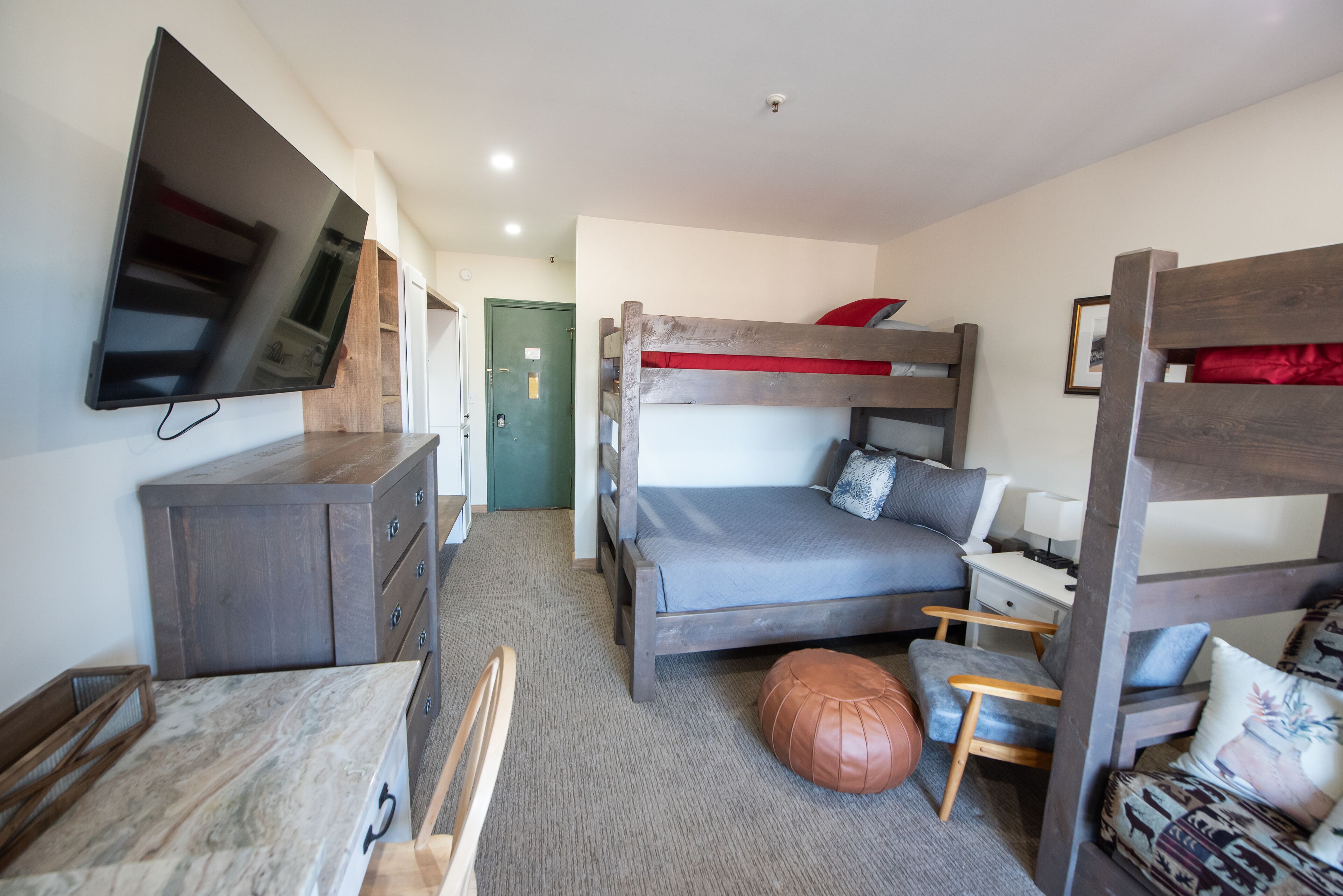 Un dormitorio con una cama litera, un escritorio, una silla, un televisor y un armario.