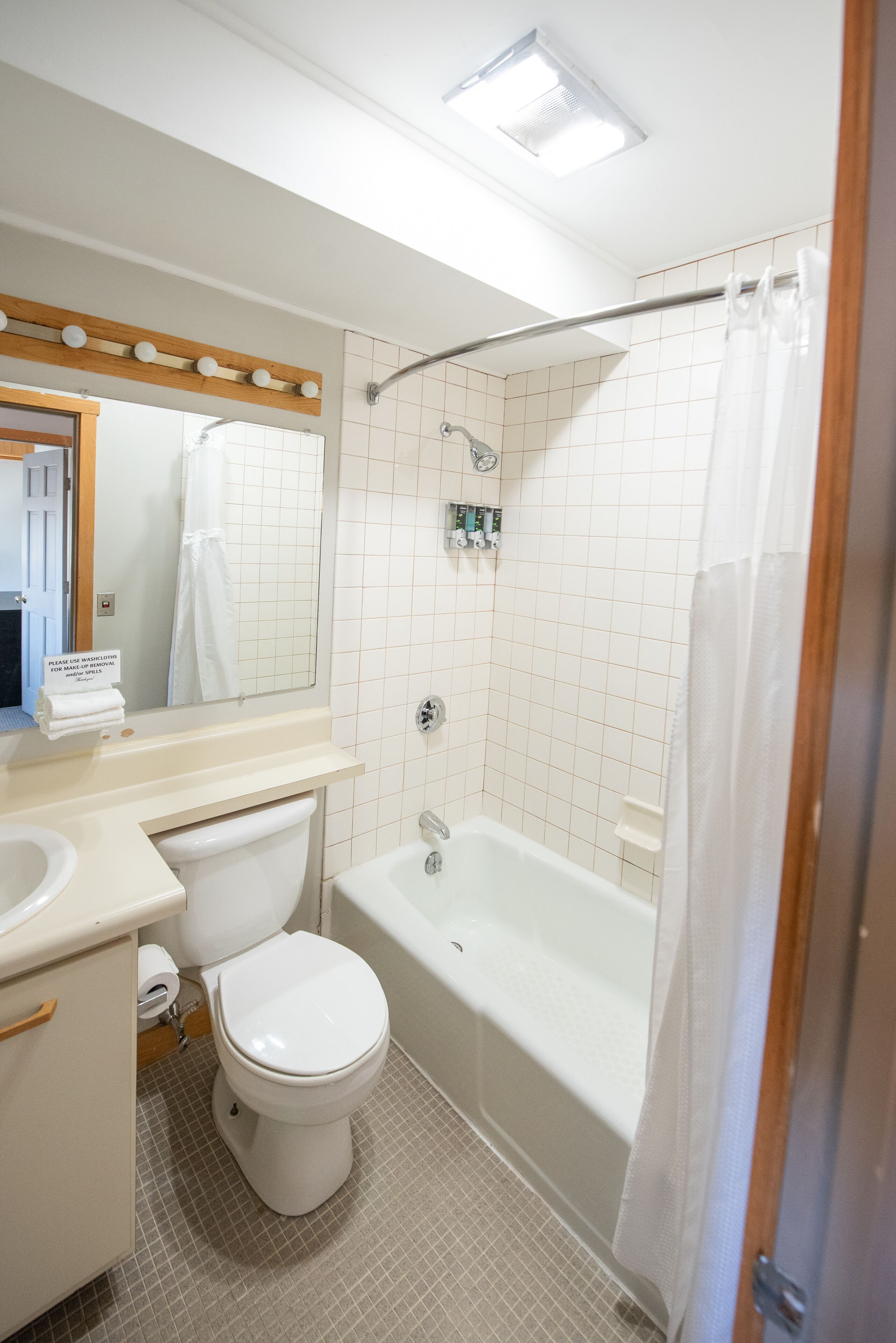 A bathroom with a toilet, sink, mirror, and bathtub.