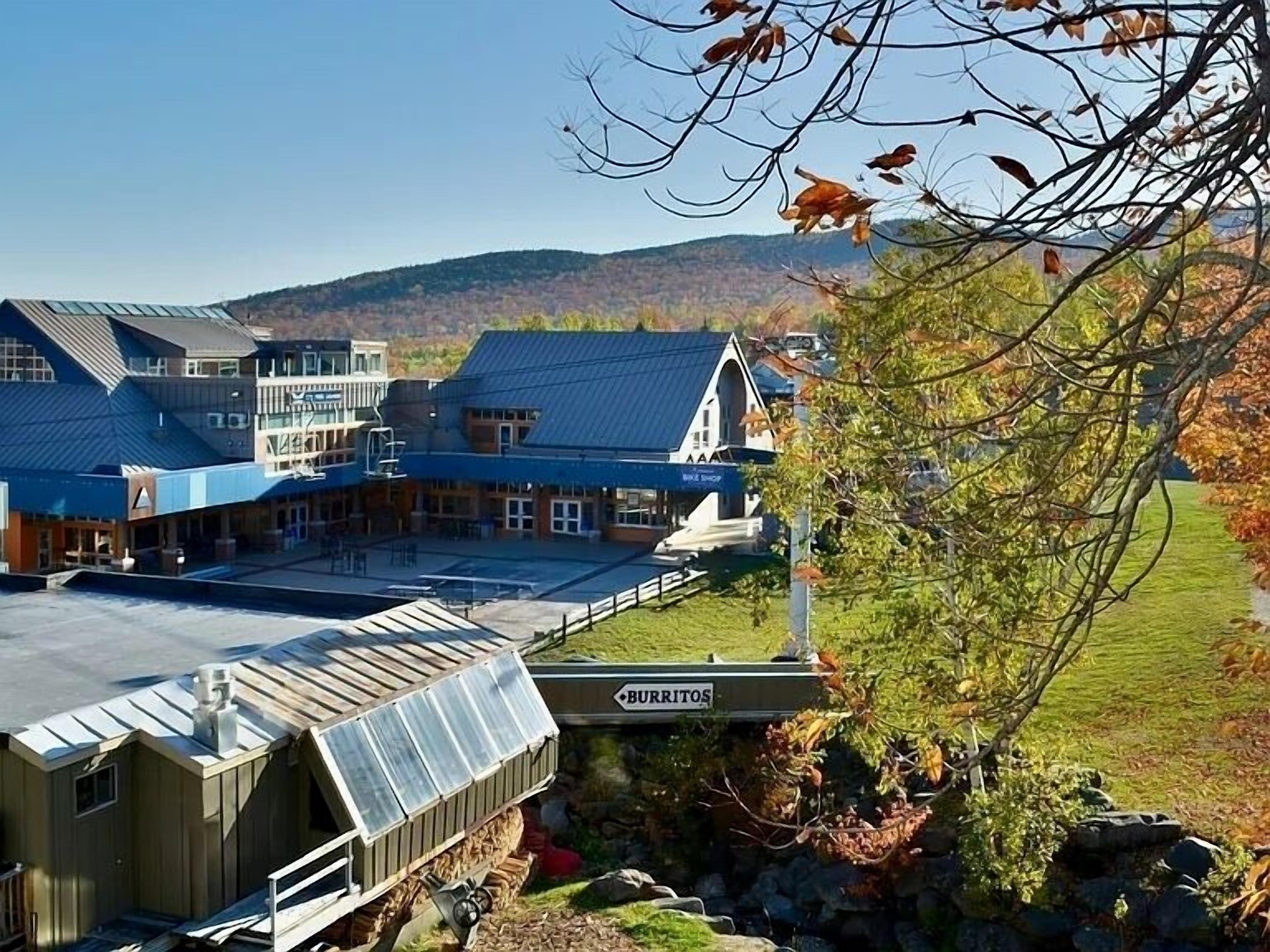 A building with a large patio area, a sign for 'Burritos', and a view of hills in the background.