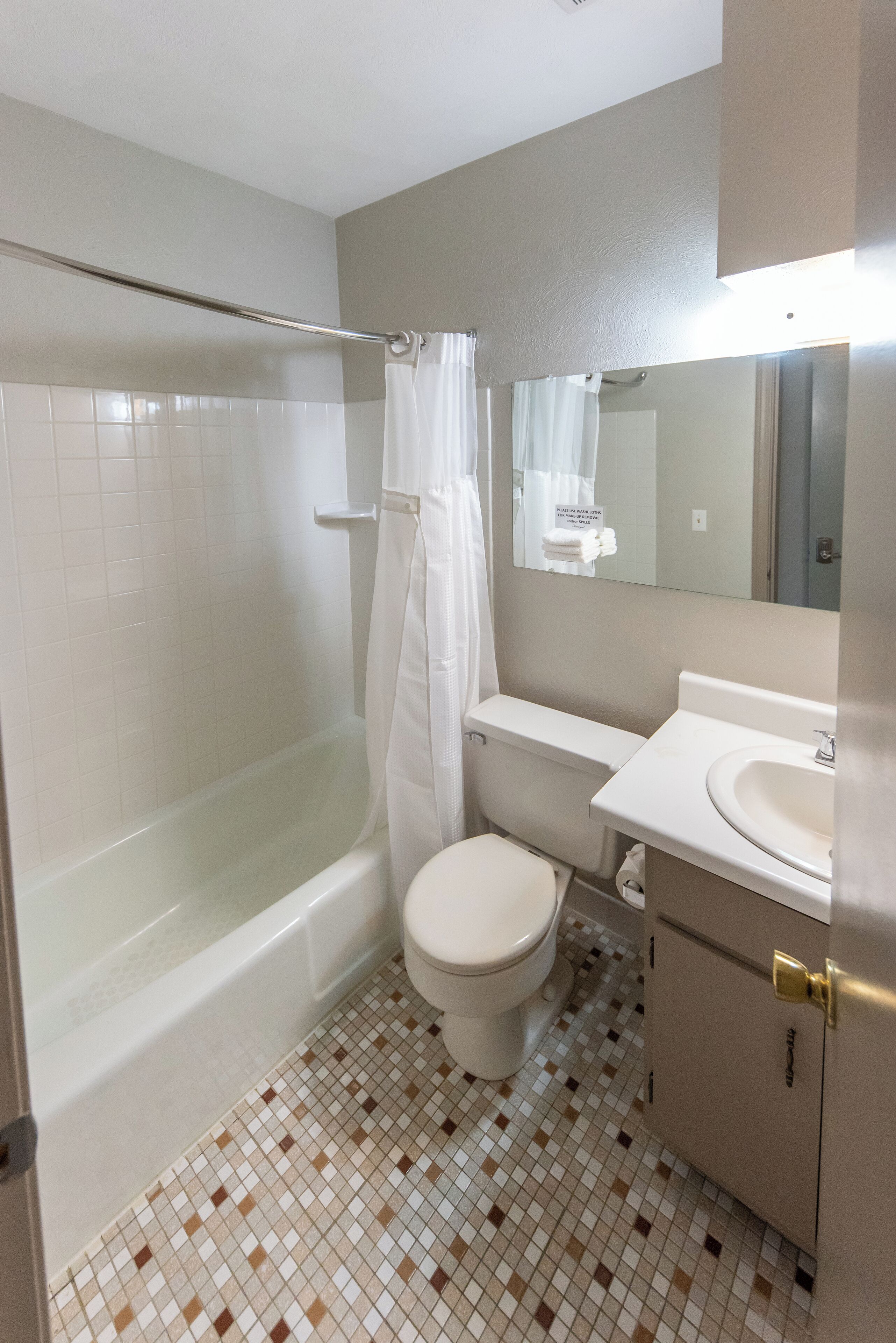 A bathroom with a bathtub, toilet, sink, and a mirror.