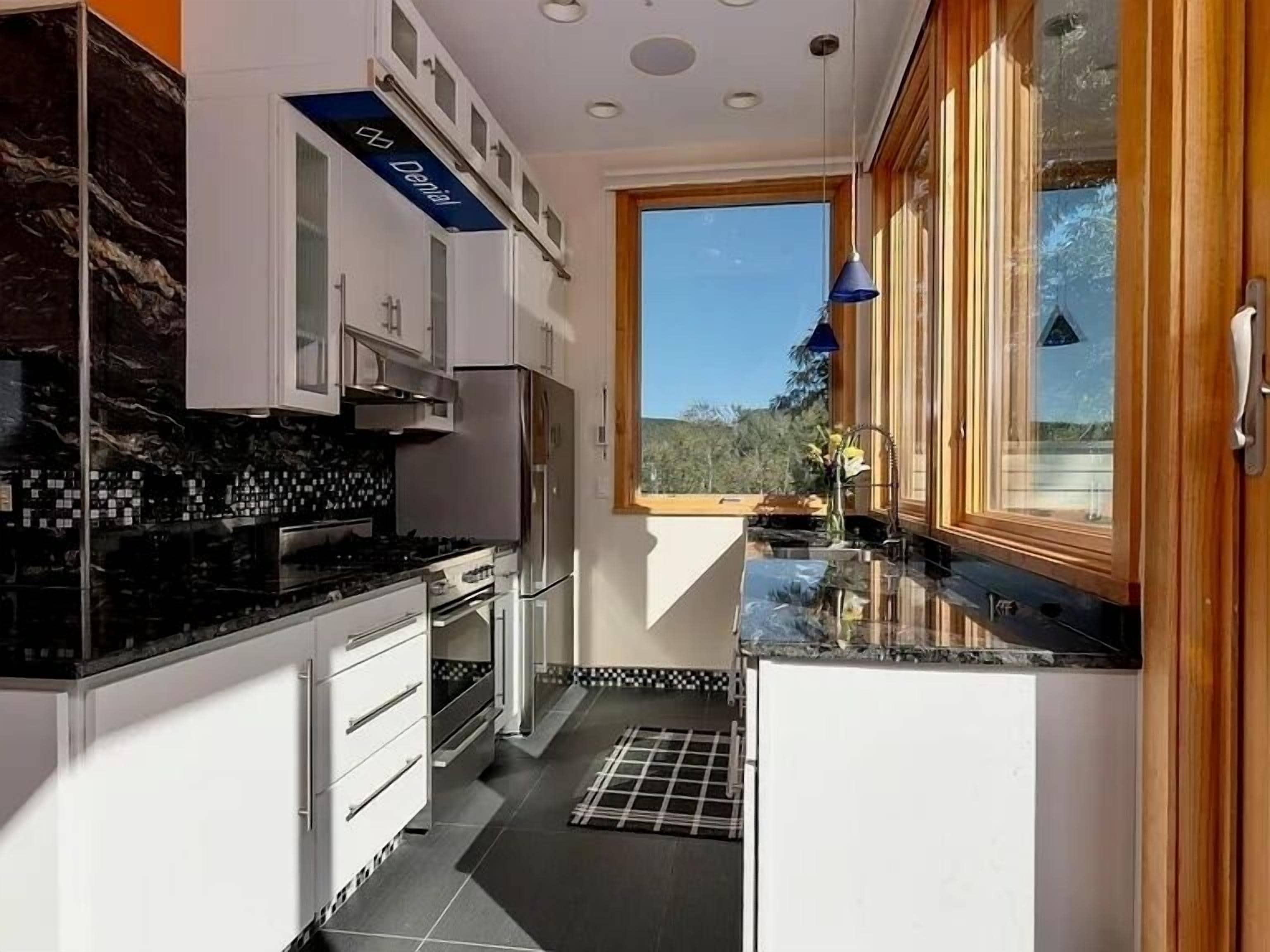 A modern kitchen with white cabinets, a black countertop, and a window with a view of the outdoors.