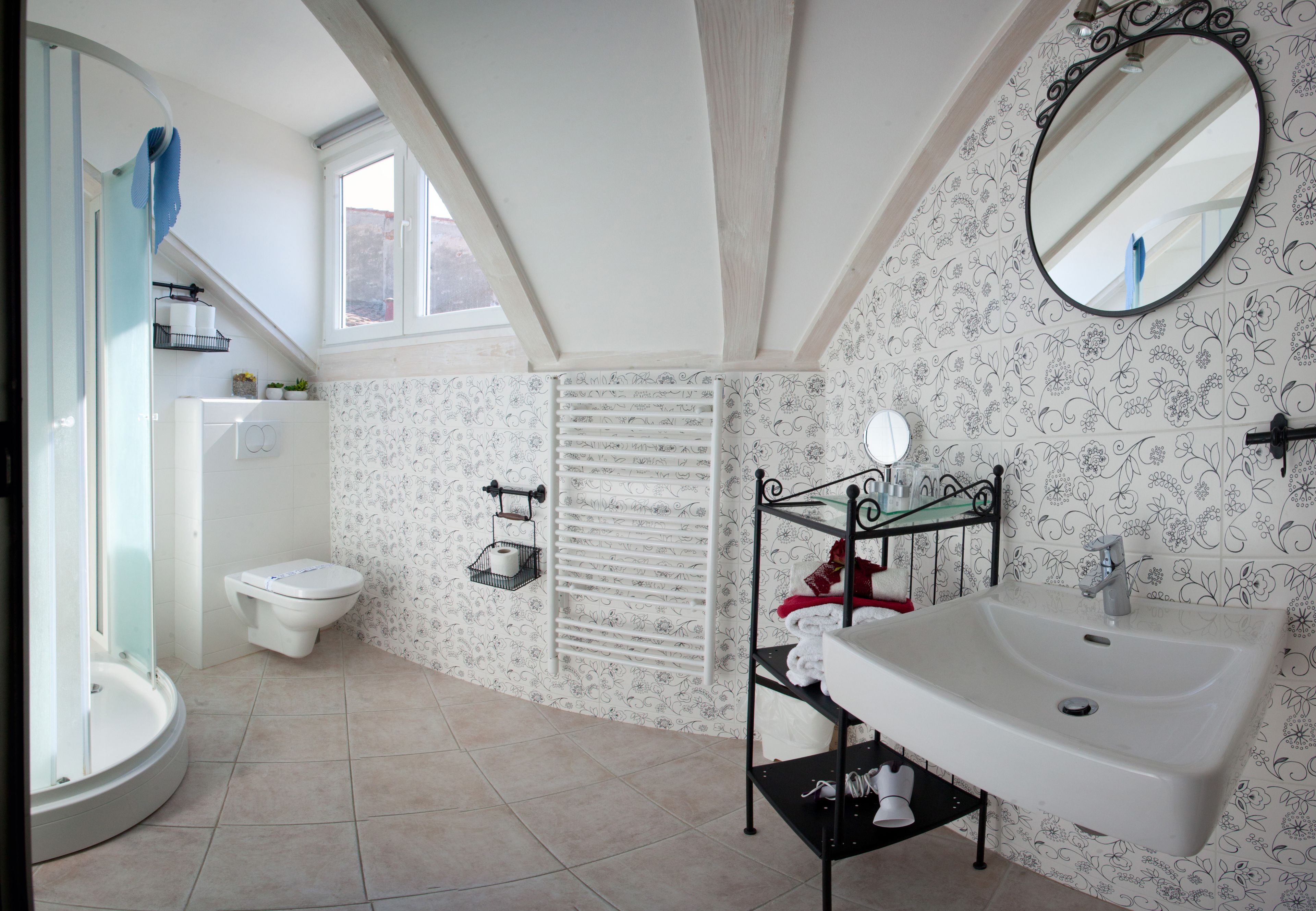 A bathroom with a white sink, a toilet, a shower, and a window.