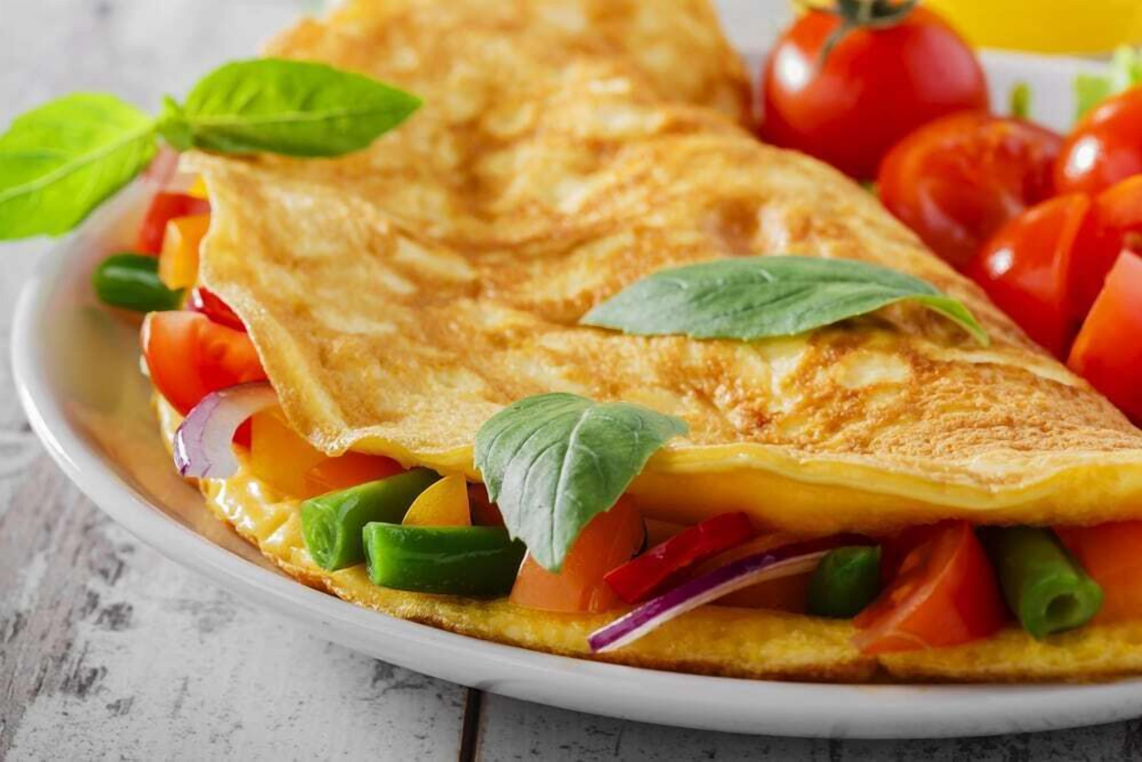 A folded omelette with vegetables and basil leaves.