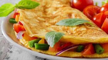 A folded omelette with vegetables and basil leaves.
