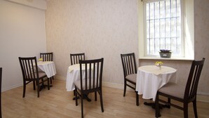 Un coin repas comprenant quatre chaises et tables en bois, une fenêtre donnant sur un paysage agréable et un luminaire au plafond.
