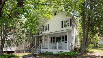 A two-story house with a porch, surrounded by trees and a well-maintained garden.
