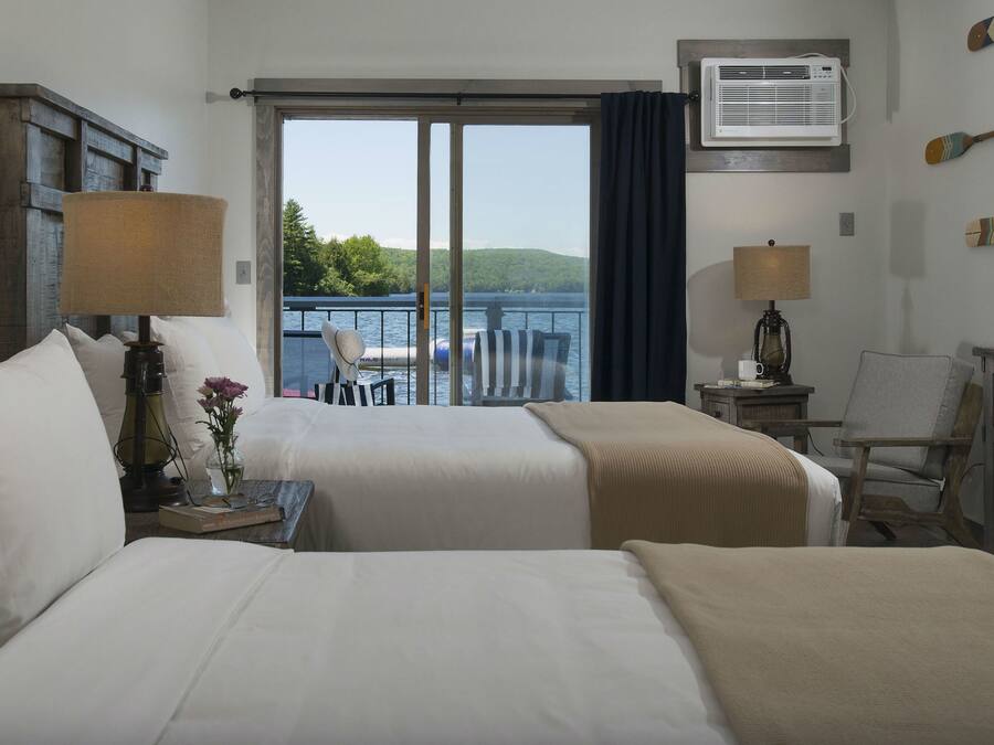 Habitación de hotel con dos camas, un escritorio, una silla, una lámpara, un televisor y vista al lago.