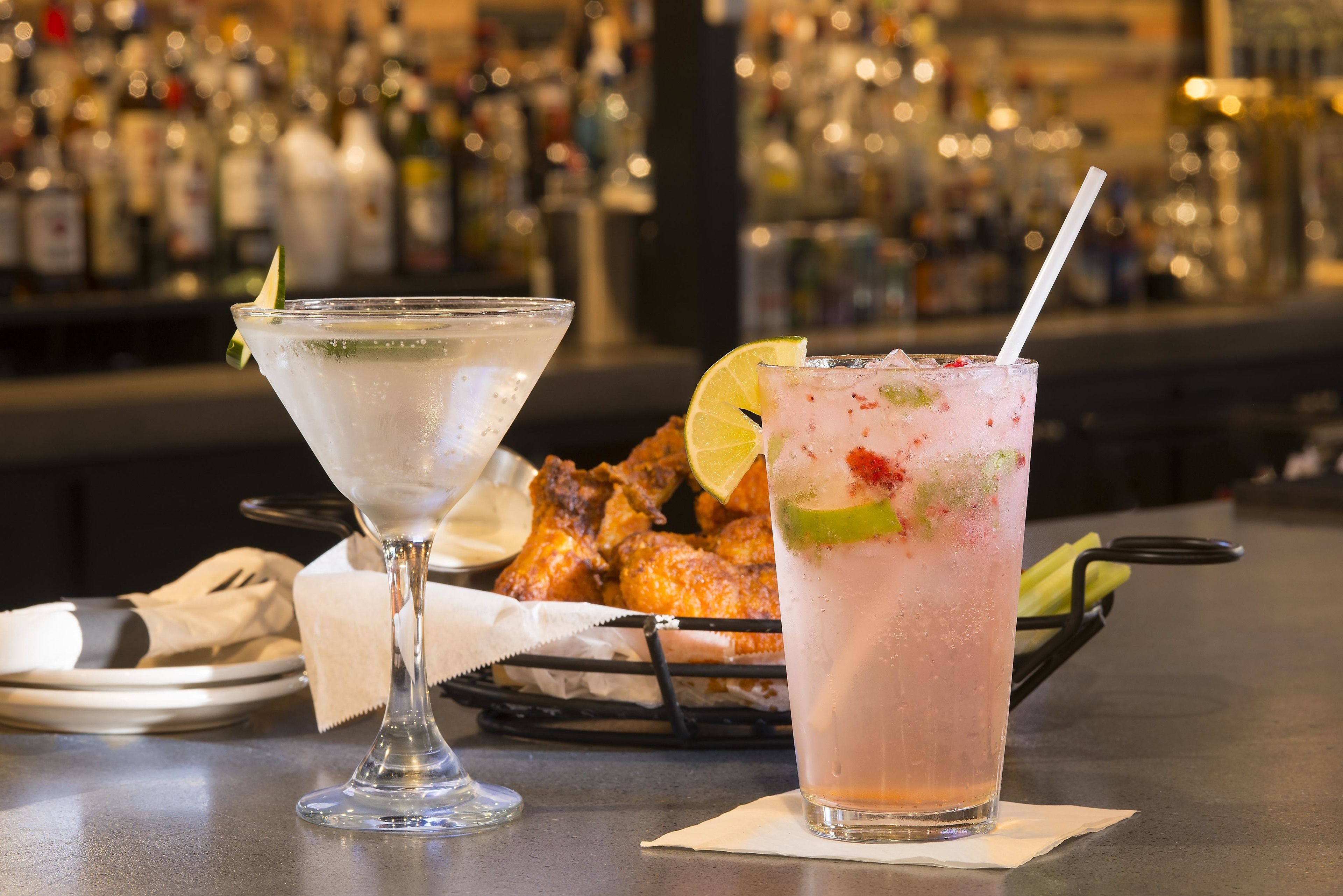 Un bar avec deux cocktails, un panier de poulet frit et un comptoir.