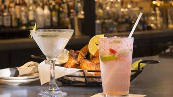 Un bar avec deux cocktails, un panier de poulet frit et un comptoir.