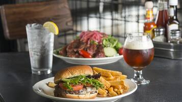 Un repas composé d’un hamburger, de frites et d’un verre de bière, le tout posé sur une table.