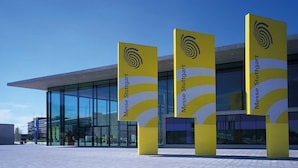 A modern building with large glass windows and yellow signage reading "Messe Stuttgart". - Appartments Drei Morgen (Leinfelden-Echterdingen)