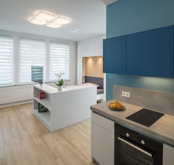 Eine moderne Küche mit integrierter Kochinsel, einem schwarzen Induktionskochfeld und einem Backofen.
