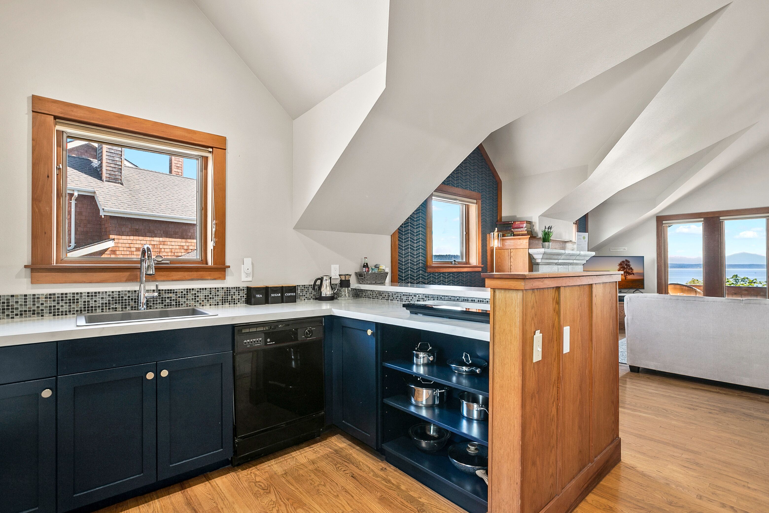 A modern kitchen with dark cabinets, a dishwasher, and a wooden island.