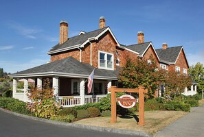 A brick house with a porch, a sign for Sandoval Inn, and an American flag.