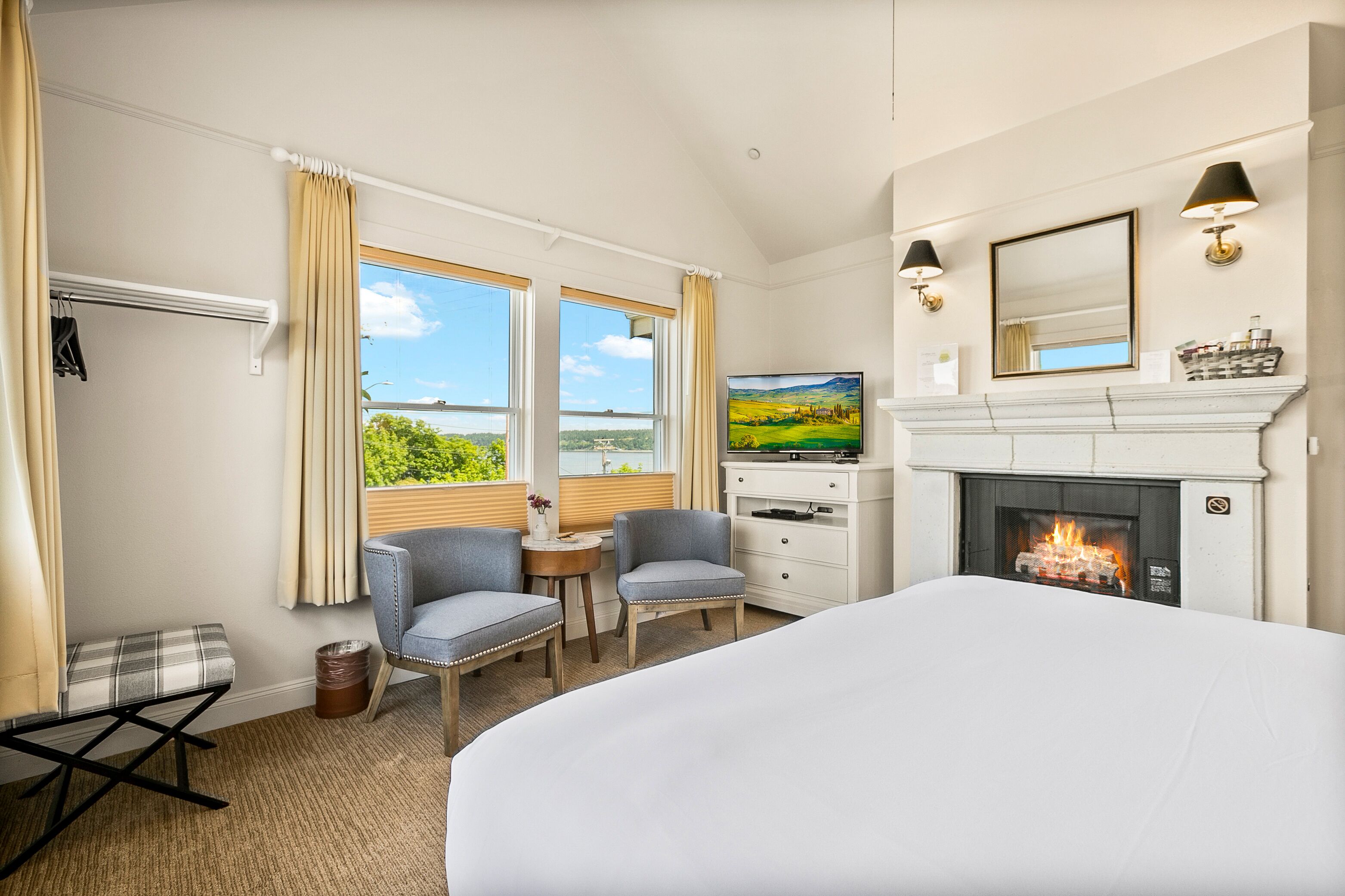 A hotel room with a bed, a television, a fireplace, and a view of the outdoors.