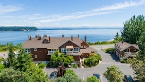 Une grande maison en briques avec un balcon, une allée et une vue sur un lac.