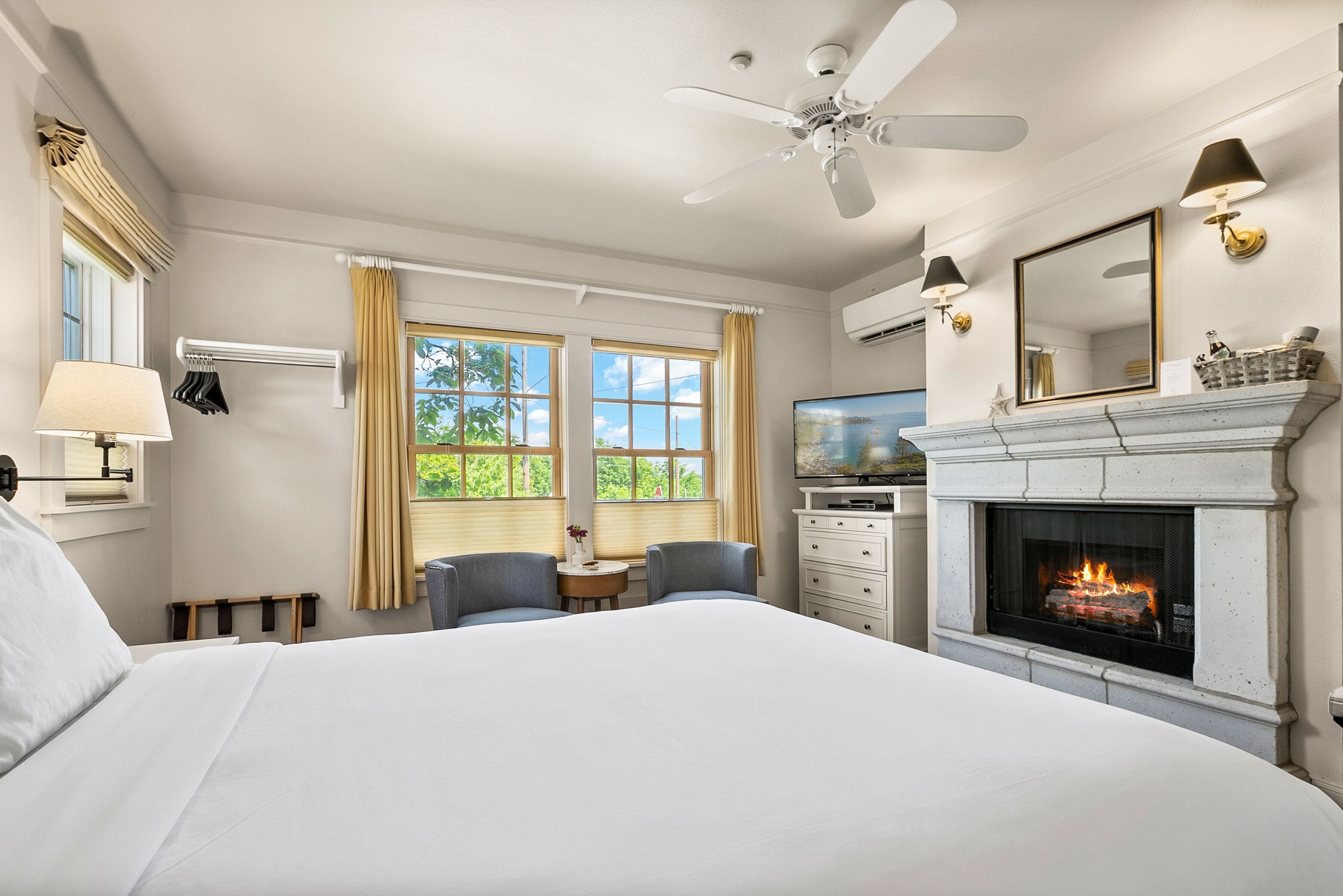 Habitación de hotel con una cama grande, chimenea, televisor y ventilador de techo.