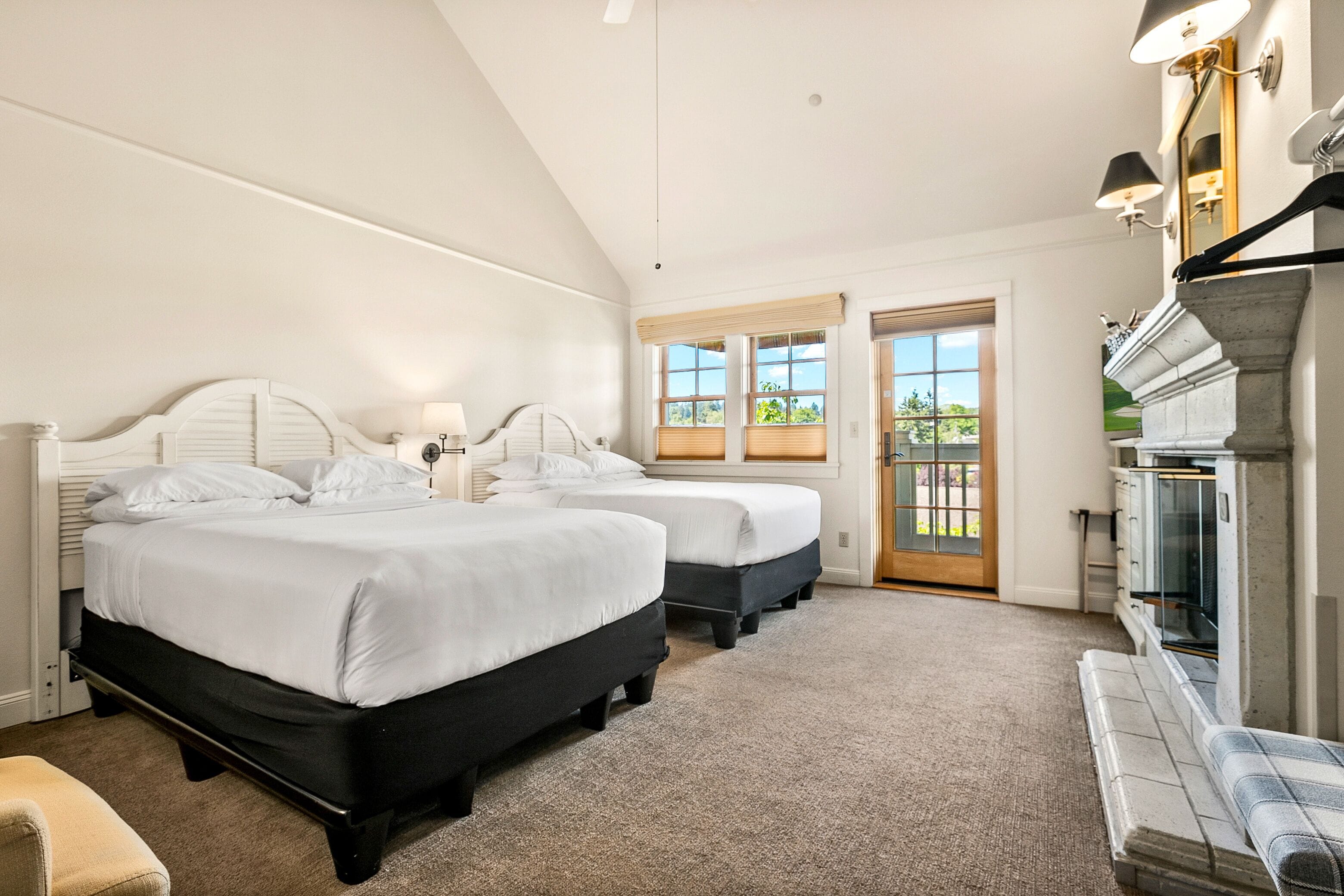A bedroom with two beds, a fireplace, and a view of the outdoors.