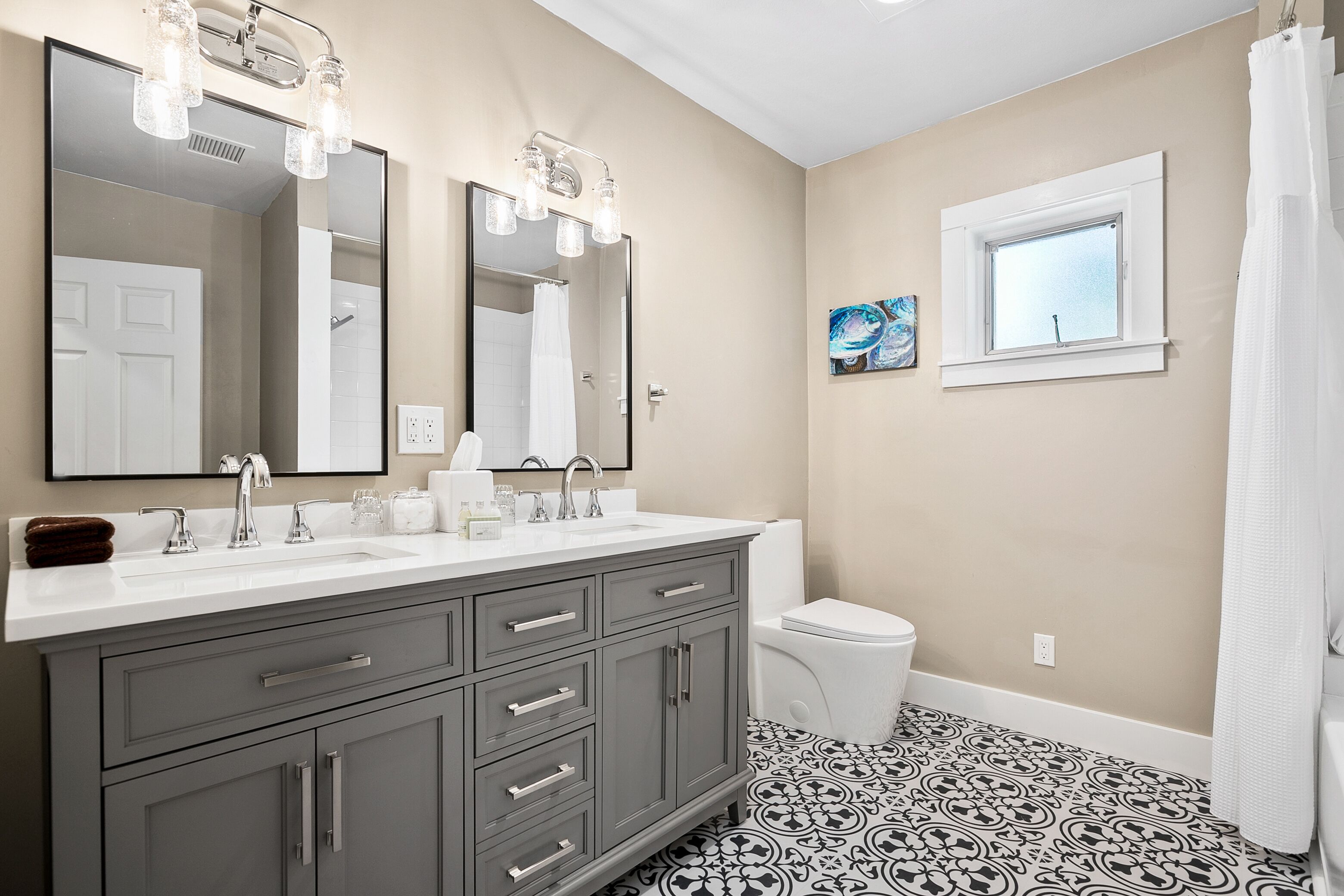 A bathroom with a double sink vanity, a toilet, a window, and a shower curtain.