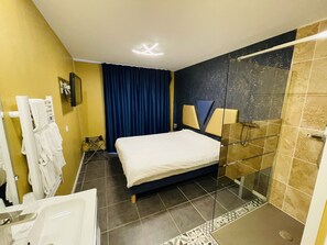 Een hotelkamer met een bed, een douche en een badkamer met een wastafel en spiegel.