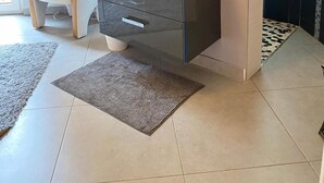 Un baño moderno con tocador, espejo y una silla.