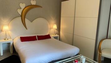 A hotel room with a large bed, two bedside lamps, a glass coffee table, and a wardrobe.