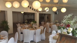 Un salón de banquetes con mesas redondas, manteles blancos y sillas.