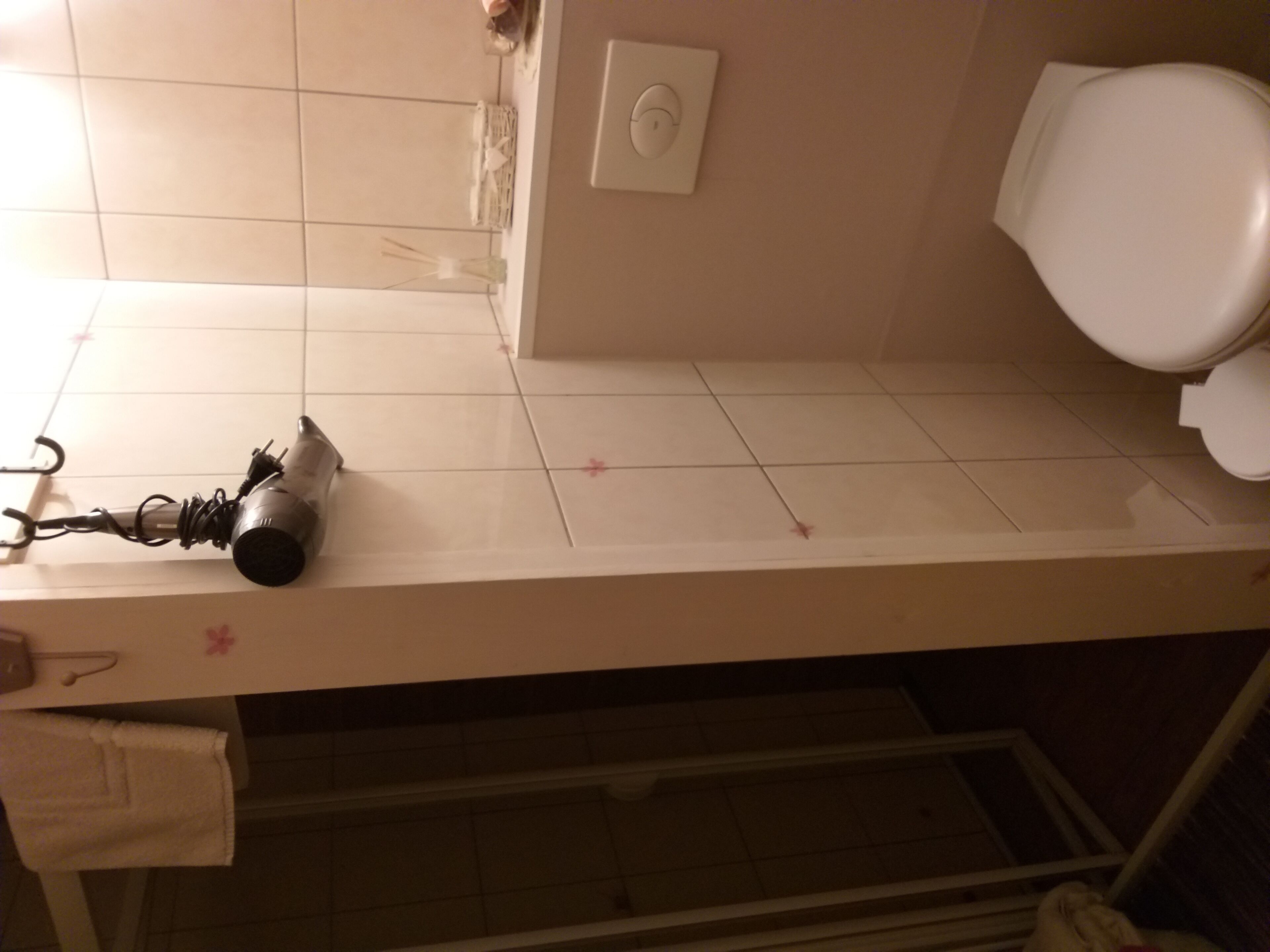 A bathroom with a white sink, a towel, and a hairdryer on the counter.