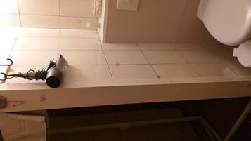 A bathroom with a white sink, a towel, and a hairdryer on the counter.