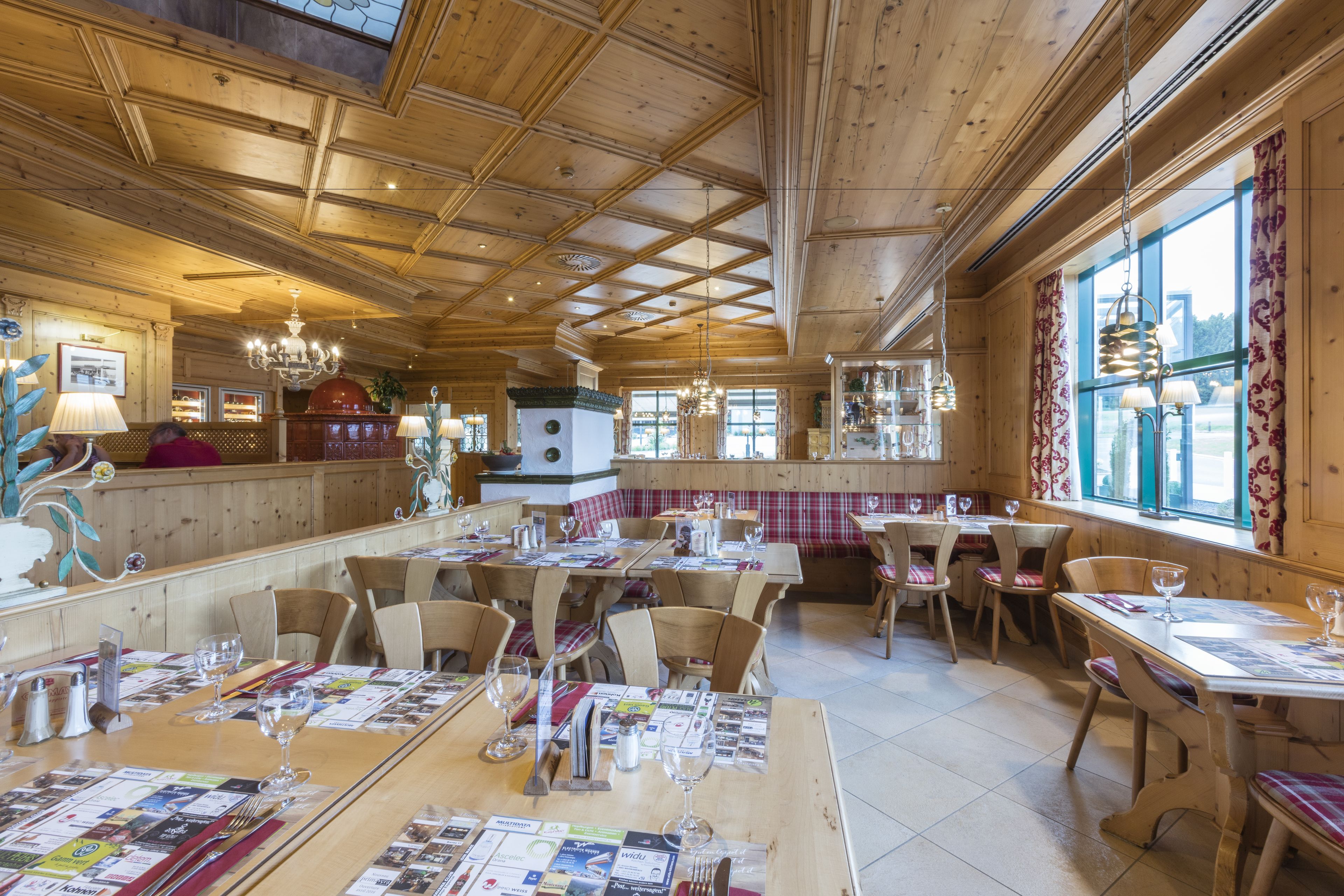 A restaurant with wooden interiors, multiple tables, and chairs.