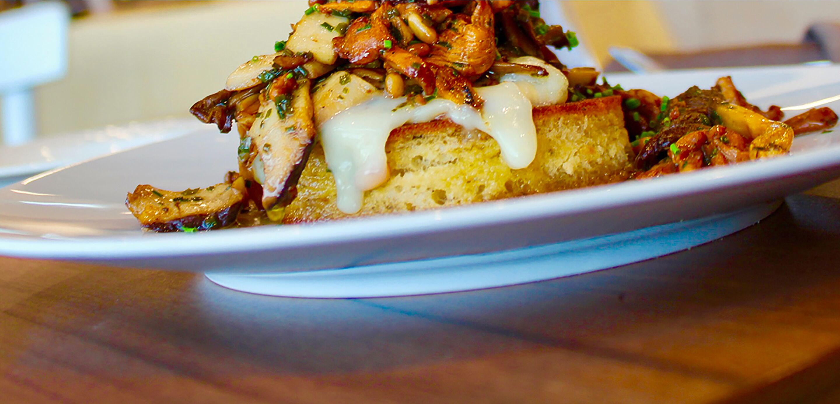 A plate of food with a golden-brown crust, topped with mushrooms and a creamy sauce.