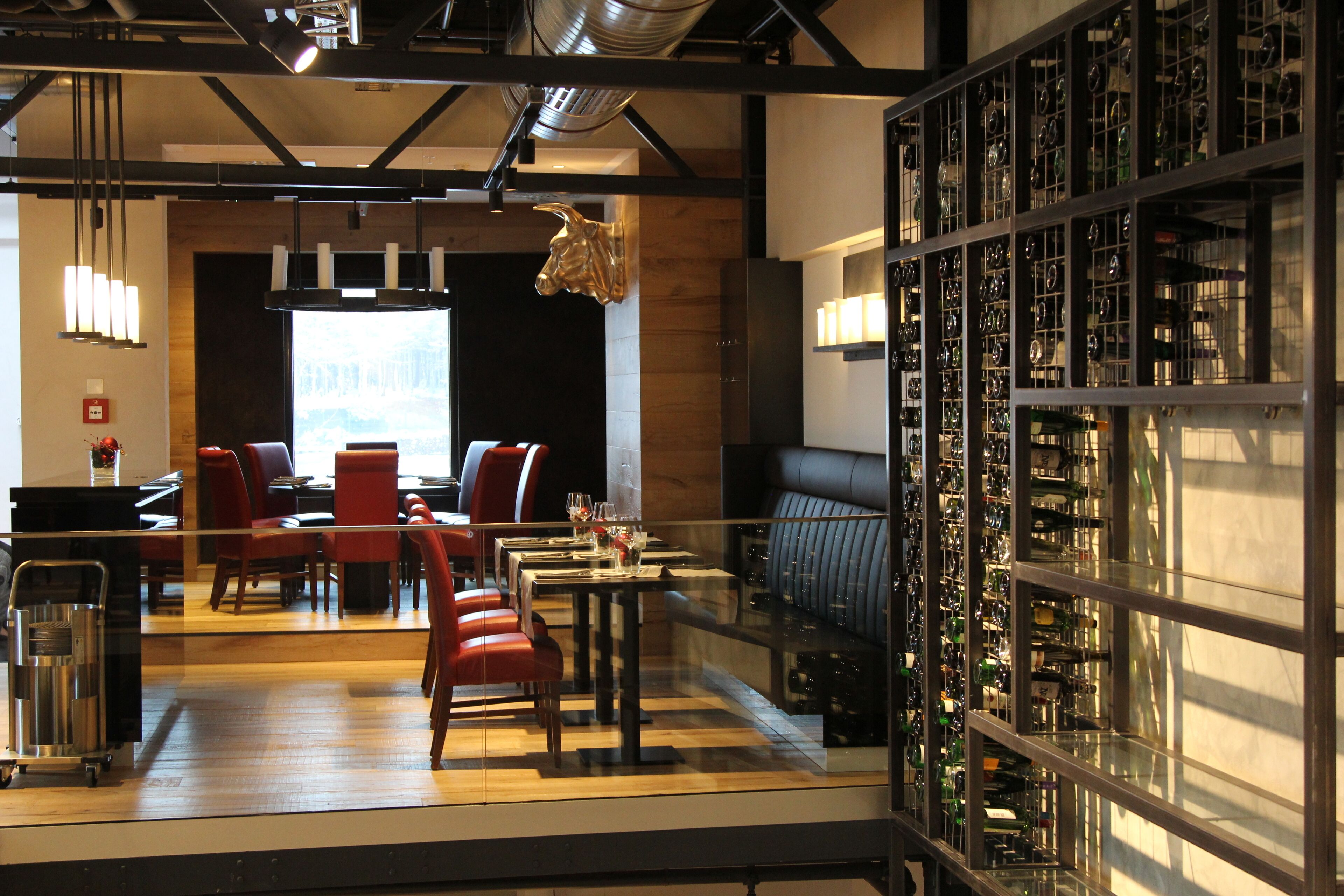 A modern restaurant with a bar area, seating, and a wine display.