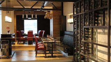 A modern restaurant with a bar area, seating, and a wine display.