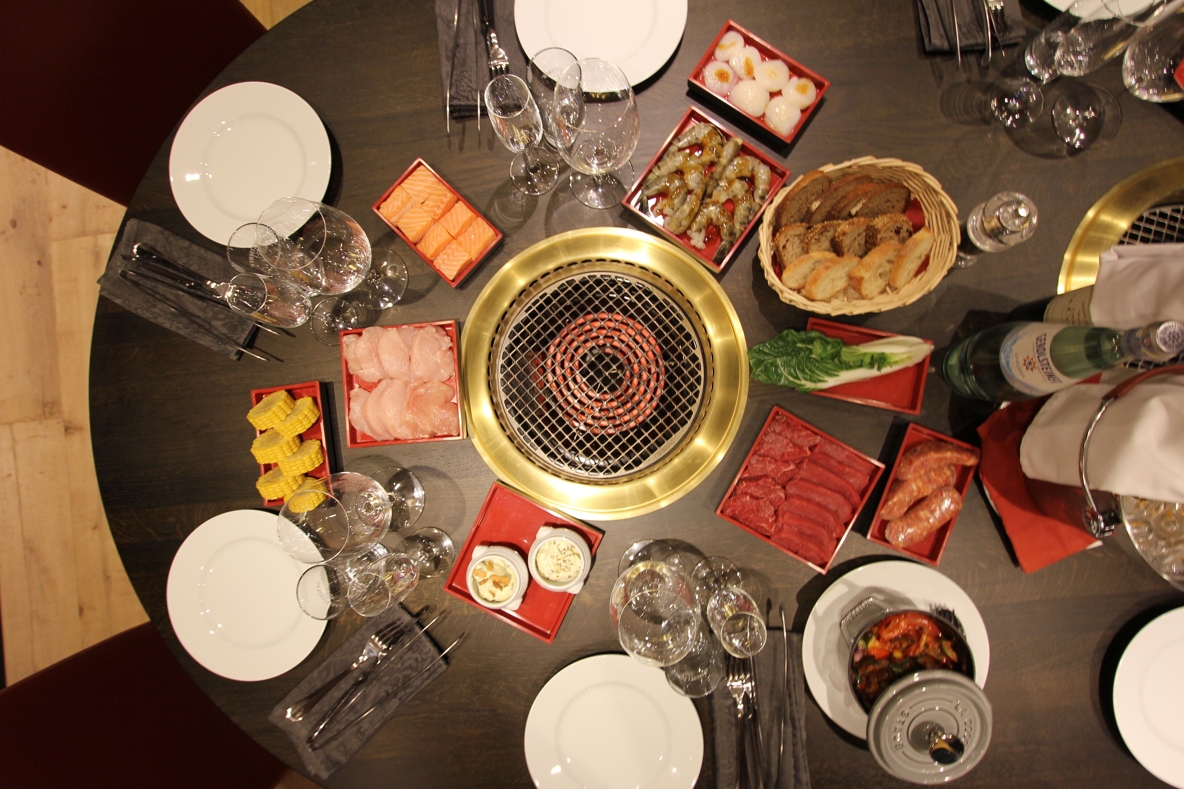 Una mesa redonda para comer con varios platos, vasos y cubiertos.