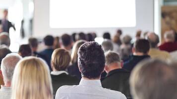 A group of people seated in a conference room facing a presentation.