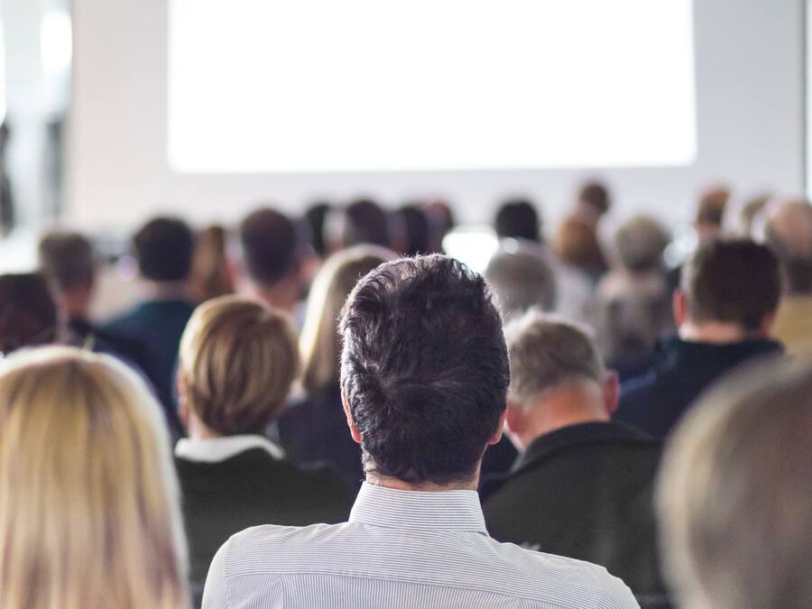 A group of people seated in a conference room facing a presentation.