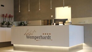 A hotel reception desk with a modern design, featuring a nameplate that reads "hotel Wemperhardt."